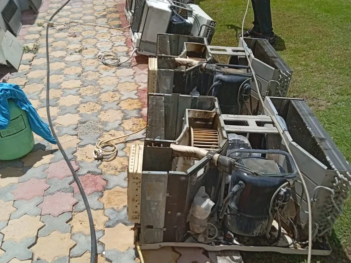 Haji AC technician deep-washing a full row of AC units during a bulk maintenance job