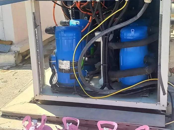 Open AC control panel with compressors and R410A refrigerant bottles during a Haji AC repair